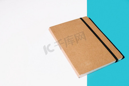 文件封面设计摄影照片_棕色封面笔记本白色蓝色背景