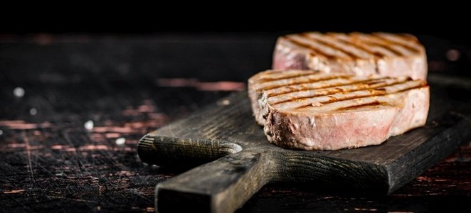 美味的烤金枪鱼牛排放在砧板上。在一个质朴的黑暗背景。高质量的照片。美味的烤金枪鱼牛排放在砧板上。 