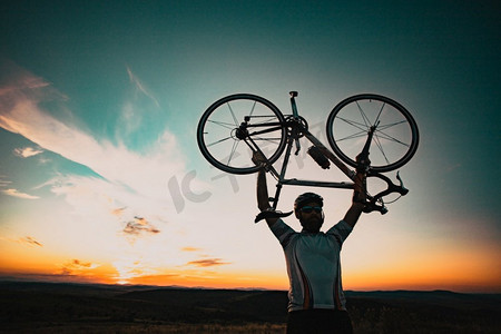 骑自行车的silhoutte与自行车提高到天空比赛和胜利概念