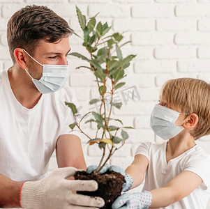 父子戴着医用口罩在家中学习一起种植