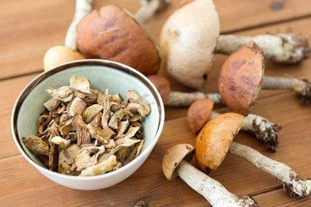 烹饪、食品和烹饪概念-木质背景碗中的干蘑菇。木质背景碗装干蘑菇