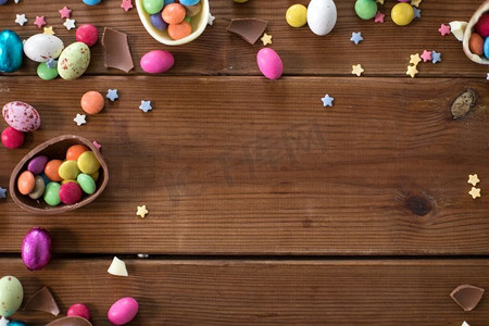 复活节，糖果和糖果概念—巧克力蛋和糖果滴在木背景。巧克力蛋和糖果滴在木桌上