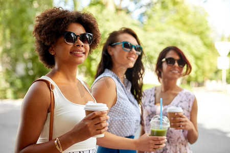 休闲、人情、友谊的概念—快乐的女人或朋友带外卖饮料夏日公园。快乐的女人或朋友与饮料在夏季公园