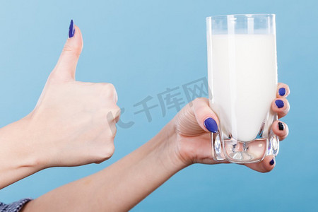 健康饮品，营养好，奶制品理念。女子手拿着一杯牛奶，露出拇指向上的手势。女人手拿着牛奶杯
