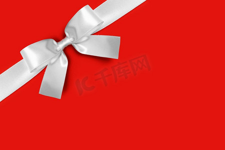 闪亮的白色缎子缎带和弓在红色背景。节日礼物的概念。闪亮的白色缎丝带蝴蝶结
