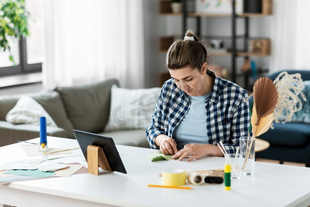 DIY，艺术和爱好概念-快乐的女人在家里用平板电脑制作纸制工艺品。在家中用平板电脑制作纸制工艺品的妇女