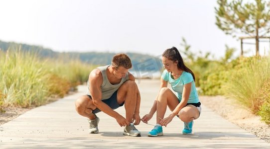 健身、运动和生活方式的概念-一对慢跑者在户外系上运动鞋鞋带。两个慢跑者系着运动鞋鞋带