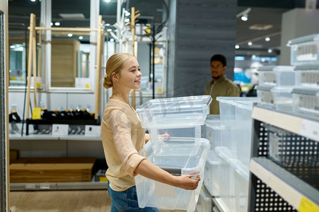 妇女购物者选择塑料储存容器在家庭用品商店。购物和零售。女性购物者在商店里选择塑料容器
