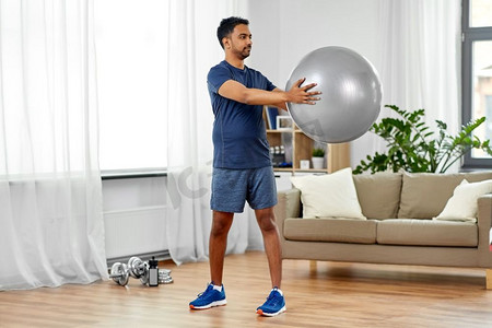 健身、运动和健康的生活方式理念--印度男子在家中带球锻炼。印度男子在家中带着健身球锻炼