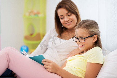人，家庭和教育理念—快乐的女儿与母亲读书在家。快乐的女孩与母亲读书在家里