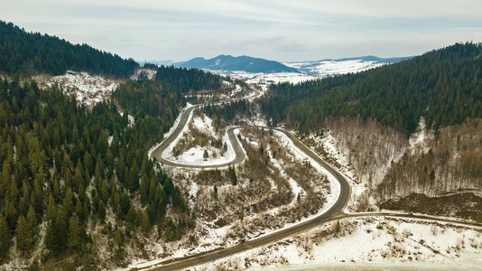 冬季雪山风景路蛇形。空中农村视图的道路通过地平线。喀尔巴阡山脉，贝斯基德山脉