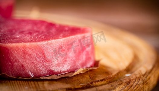 金枪鱼摄影照片_新鲜的生金枪鱼牛排在桌子上。在一个木制的背景。高质量的照片。新鲜的生金枪鱼牛排在桌子上。 