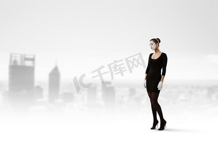 妇女哑剧在黑色西装站在城市风景背景。混合媒体。年轻女子哑剧。混合媒体