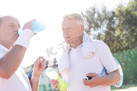 夏天站在网球场上，看起来像是资深朋友的成熟男子在喝瓶子