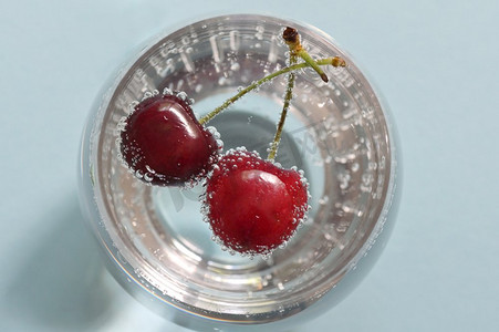 空气和水摄影照片_一杯水和新鲜樱桃，带气泡