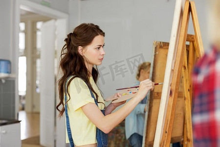艺术学校，创造力和人的概念—妇女与画架，调色板和画笔绘画在工作室。妇女与画架绘画在艺术学校工作室