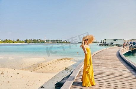 妇女穿着走在热带海滩木板路。马尔代夫的暑假