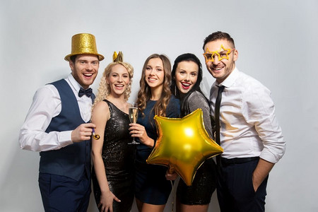 党摄影照片_庆祝，乐趣和假期概念—快乐的朋友摆在金色派对道具。快乐的朋友与黄金党道具摆姿势