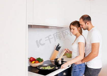 男人爱他的妻子焦化食物，带电磁炉厨房的新电炉