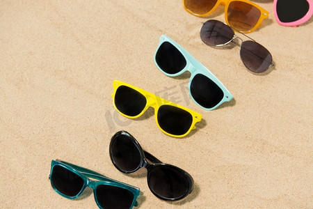 夏季，眼镜和配件概念—不同的太阳镜在沙滩上。不同的太阳镜在沙滩上