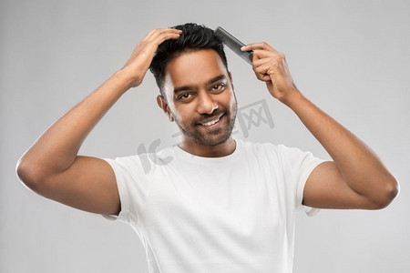 修饰，hairstinging和人的概念—微笑的年轻印度人刷头发与梳子愉快的印度人刷头发与梳子