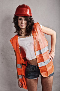 性别平等和女权主义。头戴安全帽，身穿橙色马甲的性感女孩。做建筑工人的漂亮女人。