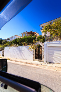 希腊一座小城市的道路。街道上装饰着附近房屋后院花园的树木，从车窗可以看到。希腊一座小城市的道路