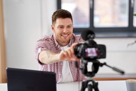 设置人摄影照片_博客，videoblog和人的概念—男性视频博客调整相机在家庭办公室。男性视频博客调整相机在家庭办公室