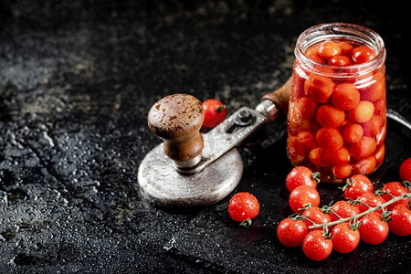 把腌制的西红柿放在石板上的罐子里。在黑色背景上。高质量的照片。把腌制的西红柿放在石板上的罐子里。