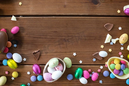 bonbon摄影照片_复活节，糖果和糖果概念—巧克力蛋和糖果滴在木背景。巧克力蛋和糖果滴在木桌上