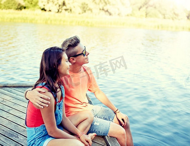 假期，假期，爱和人的概念—愉快的十几岁夫妇拥抱在河泊位在夏天。愉快的青少年夫妇拥抱在河泊位