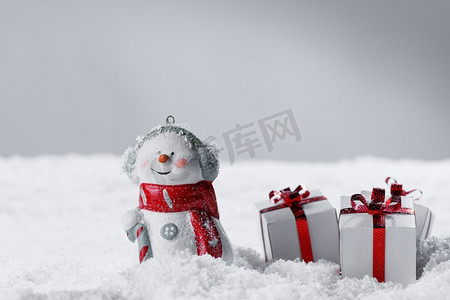 圣诞快乐及新年快乐贺卡。快乐雪人站在灰色背景与圣诞礼物。圣诞礼物雪人