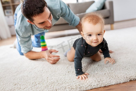 家庭，父亲和为人父母的概念—快乐的小女婴与父亲在家里爬在地板上。快乐的小女婴与父亲在家里