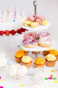 橙色生日摄影照片_派对食品和节日概念—不同的甜点和生日蛋糕。生日派对上的食物和饮料