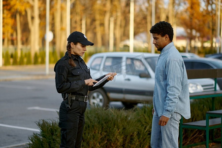 穿黑色制服的女警察在街上检查男性路人身份证。女警察检查男性路人身份证件