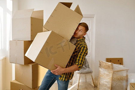 一名男子试图保持平衡，手里拿着堆叠的纸箱。搬家日和搬迁。男子试图保持平衡保持箱