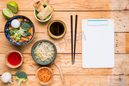 春卷酱摄影照片_泰国汤春卷酱芽豆用白色纸剪贴板木桌