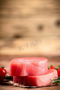 生金枪鱼配樱桃番茄和迷迭香。在一个木制的背景。高质量的照片。生金枪鱼配樱桃番茄和迷迭香。 