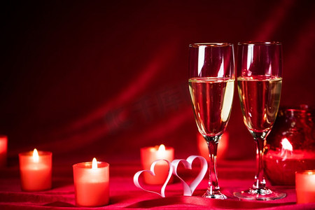 情人节庆祝活动，红丝上的香槟、蜡烛、玫瑰和红心。香槟和蜡烛