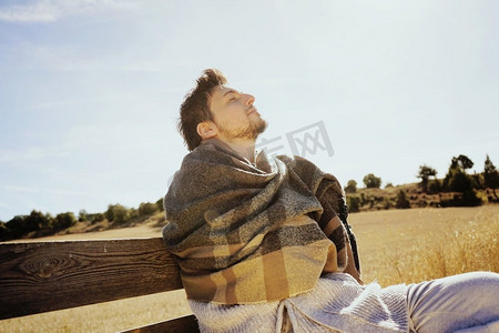 背光的人摄影照片_有眼睛关闭的一个年轻人的侧面在平静享受早晨秋天的太阳在一个黄色领域与从蓝天的背光