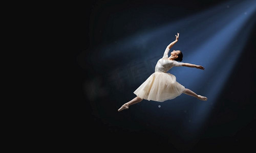 优雅的女舞蹈家在白色礼服反对黑暗背景。跳芭蕾舞演员