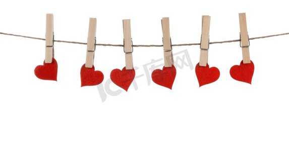 衣夹和红纸心绳上的白色背景隔绝了情人节的概念。衣夹和心形挂在绳子上