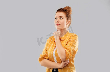 人物概念-穿着格子衬衫的红发少女抬头看着灰色的背景。穿着格子衬衫的红发少女