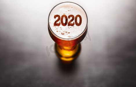 新年啤酒。黑色桌子上的啤酒泡沫上的2020标志，从上面看。2020年新年啤酒