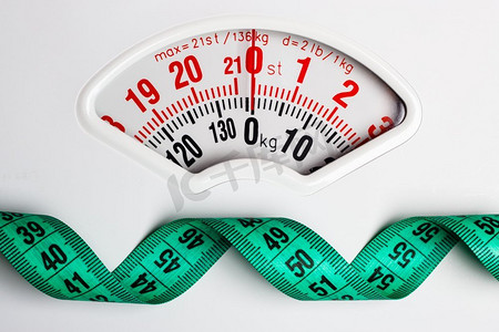 节食减肥瘦身概念。白色磅秤上的特写测量带