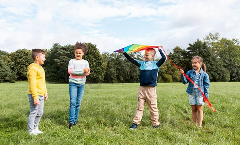 风筝玩具摄影照片_童年，休闲和人的概念—一群快乐的孩子在公园玩风筝。快乐的孩子与风筝玩在公园