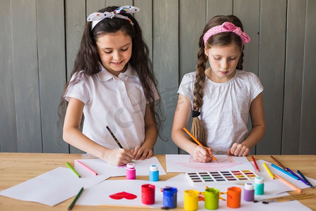 小女孩用彩色铅笔画画白纸木桌子