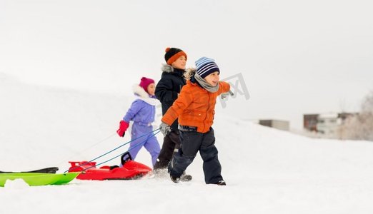 童年，雪橇和季节概念—一群快乐的小孩子在冬天雪橇。快乐的小孩子与雪橇在冬天