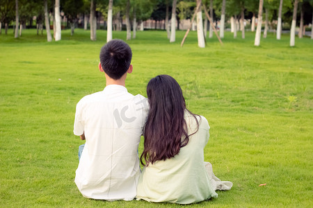 一对情侣坐在草地爱情公园夏天