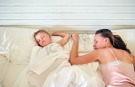 孩子和妈妈睡摄影照片_三岁学步男孩和妈妈睡在枕头上